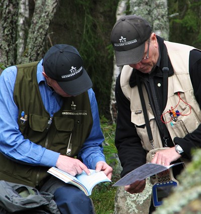 Två män studerar fältinstruktioner. Foto.