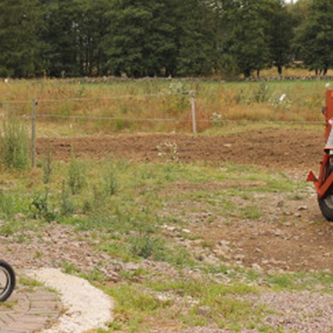 En barncykel bredvid en lantbruksmaskin, foto.