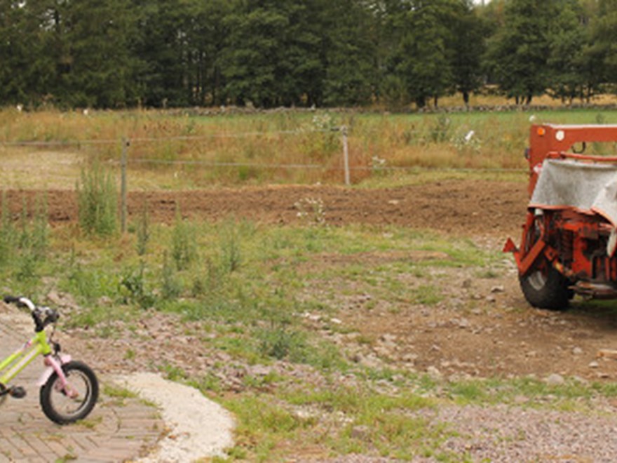 En barncykel bredvid en lantbruksmaskin, foto.