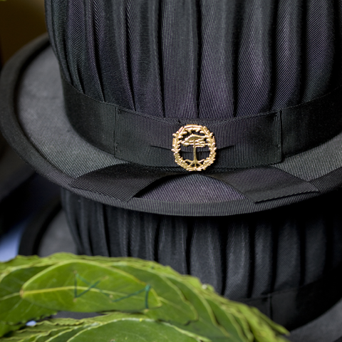Svart hatt med skogshögskolans emblem. Foto.