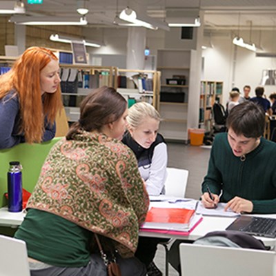 Fyra personer tittar i en bok tillsammans. Foto.