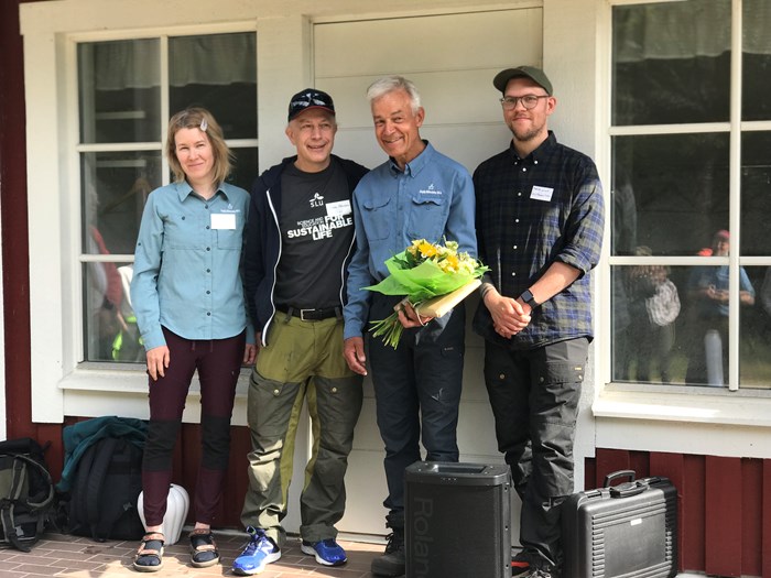 Fyra personer står framför hus. Foto.