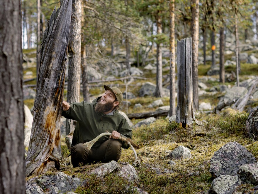 En man sitter i en skog. Foto.