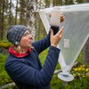 Therese Löfroth håller upp en vit burk för att studera botten. Foto.