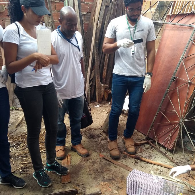 Persons looking at a small cage. Photo.