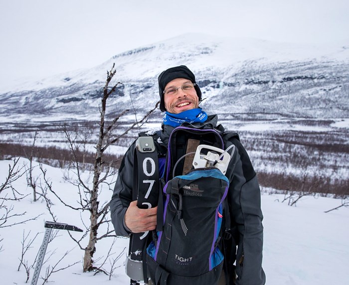 Fredrik Stenbacka i fjällmiljö, vinter, med arbetsredskap på magen. Foto.