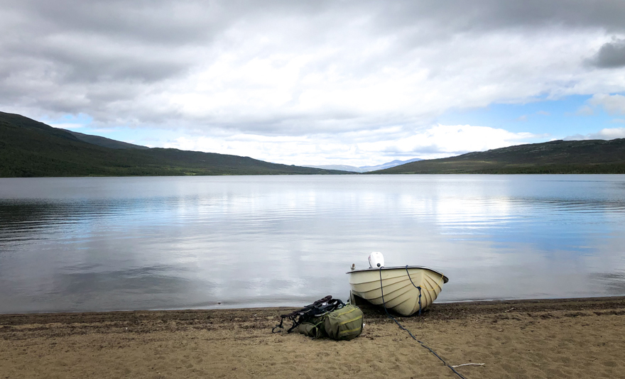  Boat on shore by mountain lake.