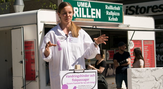 Lo iförd vit labbrock håller en presenation utomhus. Foto.