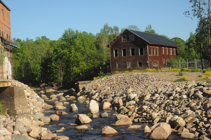 River flowing through the remains of a dam at an old mill or industry. Photo.