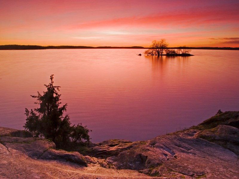 Solnedgång över en sjö. Himlen är röd. Foto.