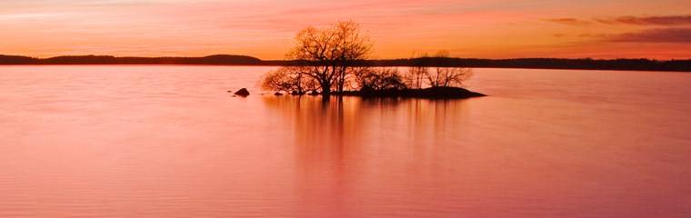 Solnedgång över en sjö. Himlen är röd. Foto.