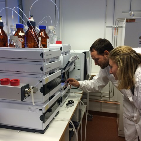 Two chemists inspecting an analysis instrument