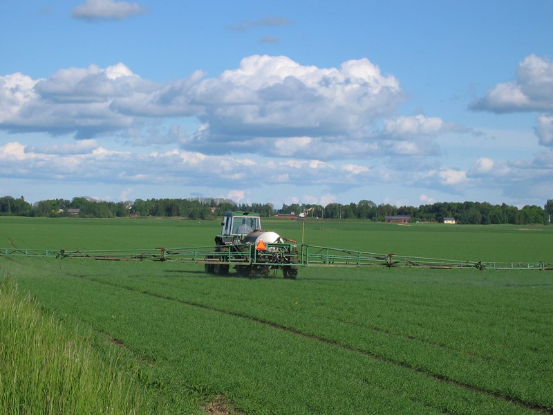 Traktor med spruta för bekämpningsmedel på åker. Foto.