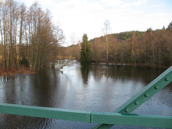 High flow and a bridge railing in the foreground. Photo.