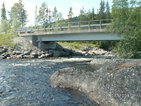 Strömmande älv under en bilbro. Foto.