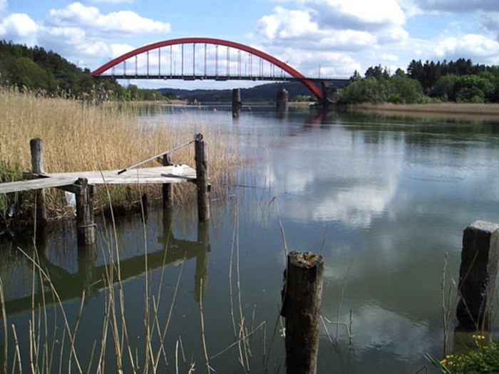 Älv med röd bro i bakgrunden. Foto.
