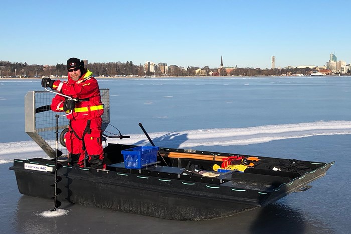 Man standing in a hydrocopter and drilling a hole in the ice. Photo.