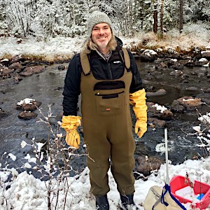 A man standing in front of a stream. Photo.