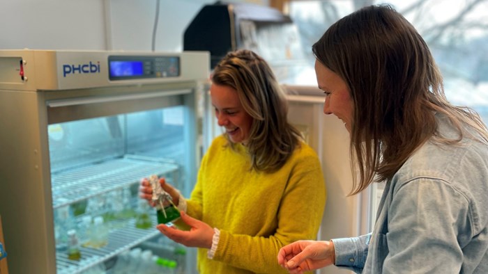 Two women loooking at sample in bottle. Photo.