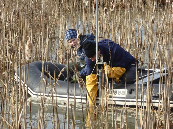 två personer i en gummiflotte ute på en våtmark. Foto.