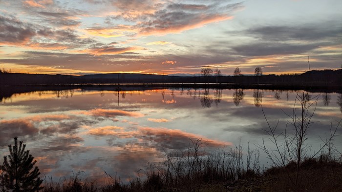 Solnedgång över sjö. Foto.