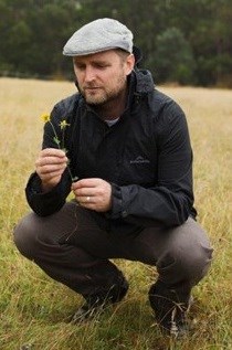 A man looks at a flower that he has in his hand.
