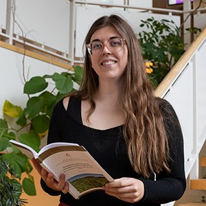 Ett porträttfoto av Brooke Micke som håller i sin doktorsavhandling.