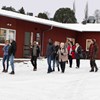 En grupp personer går i snön framför ett hus.