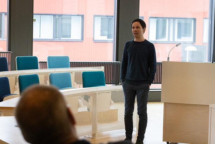 Man står bredvid podium i hörsal och talar. Foto
