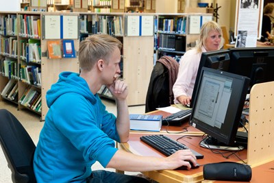 Studenter använder bibliotekets datorer, i en biblioteksmiljö