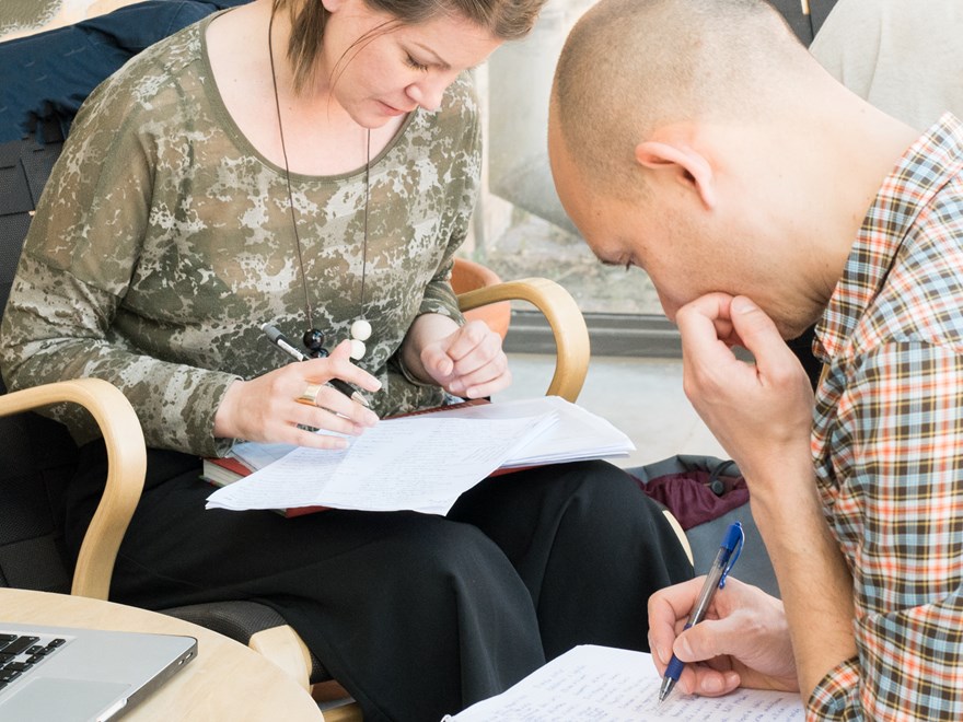 Två studenter sitter och studerar i varsin fåtölj. 