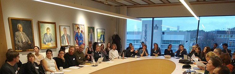 A lot of people sitting around an oval table for a meeting. Photo. 