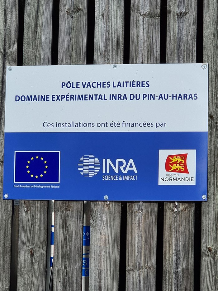 Blå skylt med EU, INRA och region Normandie. Foto.