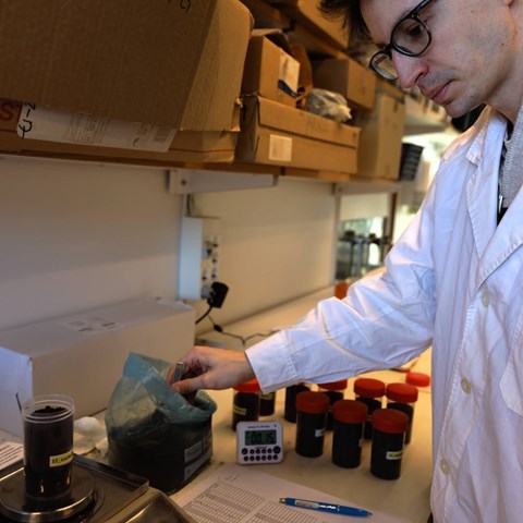 Researcher in a white coat prepare samples of biochar