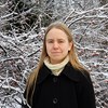 Porträttbild av Sonja Viljamaa framför en snötäckt buske