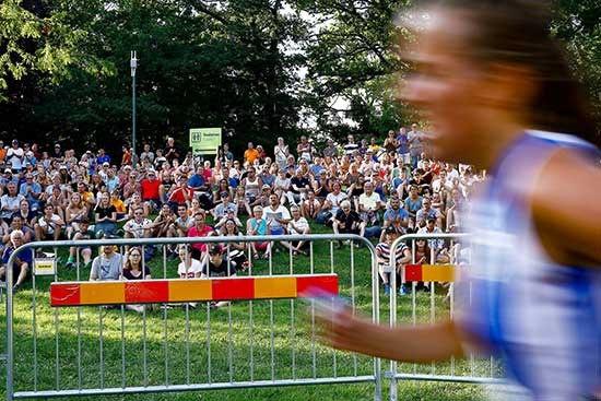An orienteer runs with the audience in the background, photo.