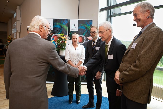Bild av kungen som hälsar på professor Thomas Kätterer och de andra talarna vid eventet.. 