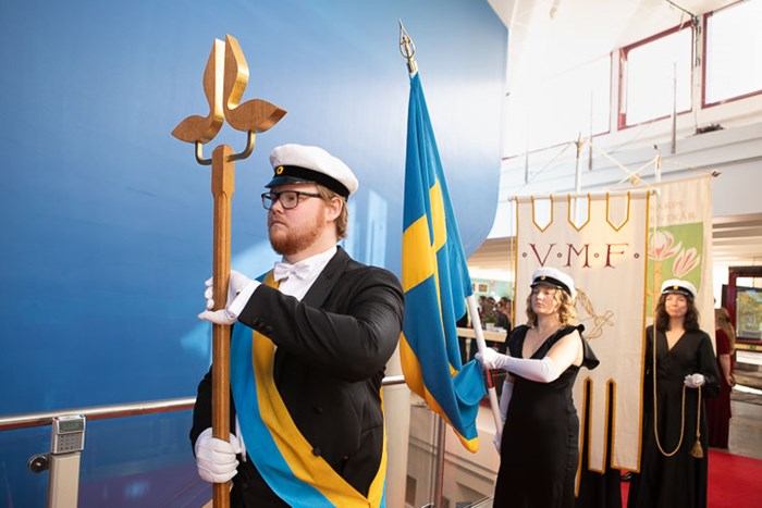 Picture of the procession lead by the student marshals carrying the student union banners.  