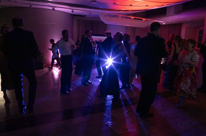 Mörka oskarpa konturer av folk på ett dansgolv. Färgglada ljuskällor lyser på golv och väggar.