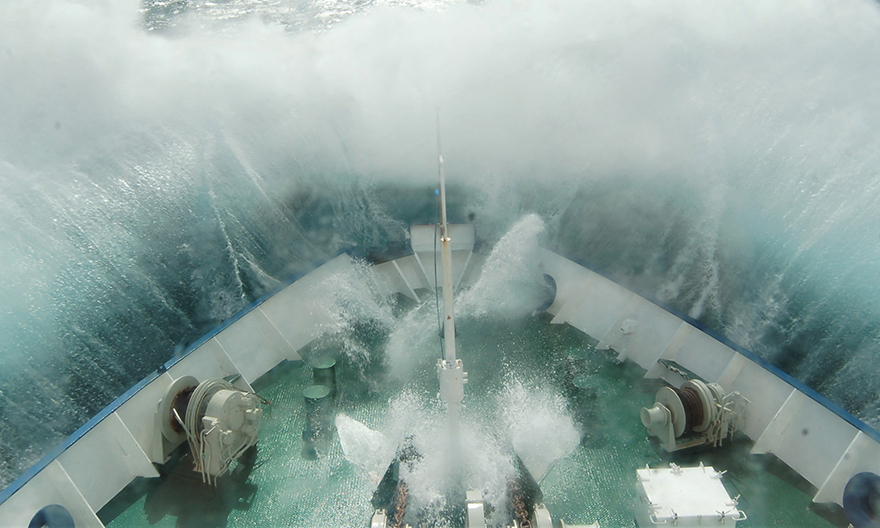 tora vågor slår över fören på ett fartyg till havs under hårt väder.