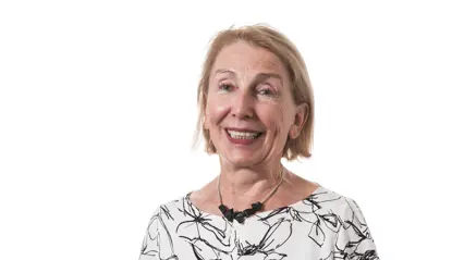 A woman wearing a blouse with a white and black pattern smiling.