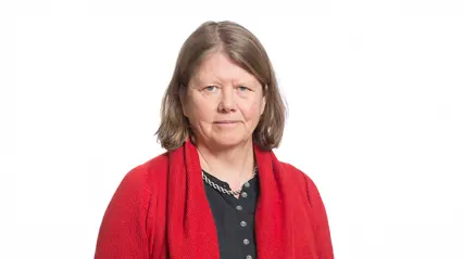 A woman with a light brown bob haircut, a red knitted cardigan and a black shirt underneith.