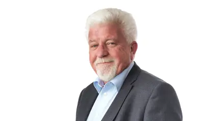 An elderly man in a suit and blue shirt.