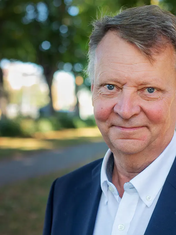 En man i kostym ler in i kameran.