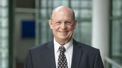 A smiling man in a dark suit.