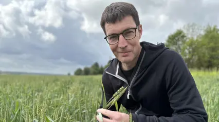 A man with dark hair and glasses sitting on a field.