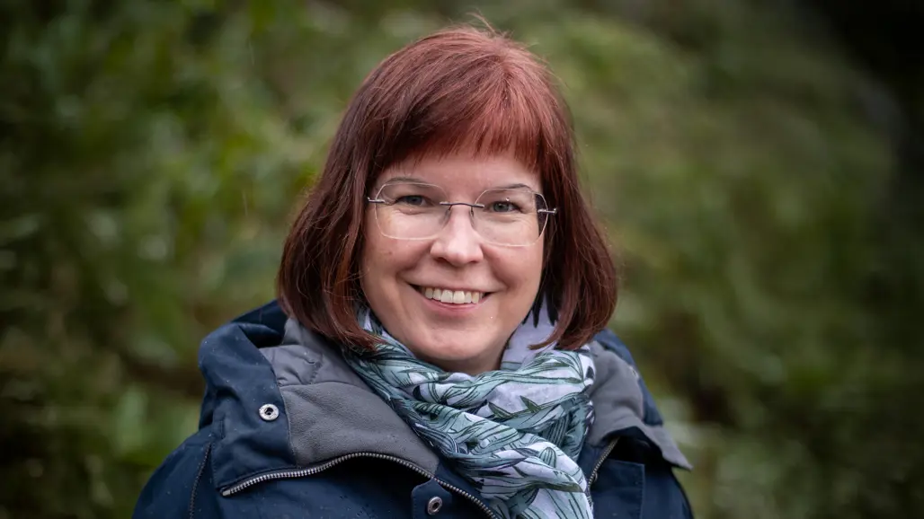 Portrait of a woman with auburn hair outdoors.