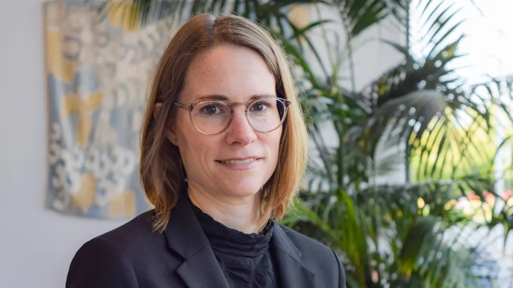 Portrait of a woman with glasses in an indoor setting with plants.