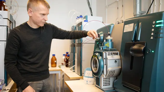 A man adjusts advanced laboratory equipment in a chemistry lab.