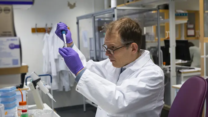 A person standing in a lab pipetting.
